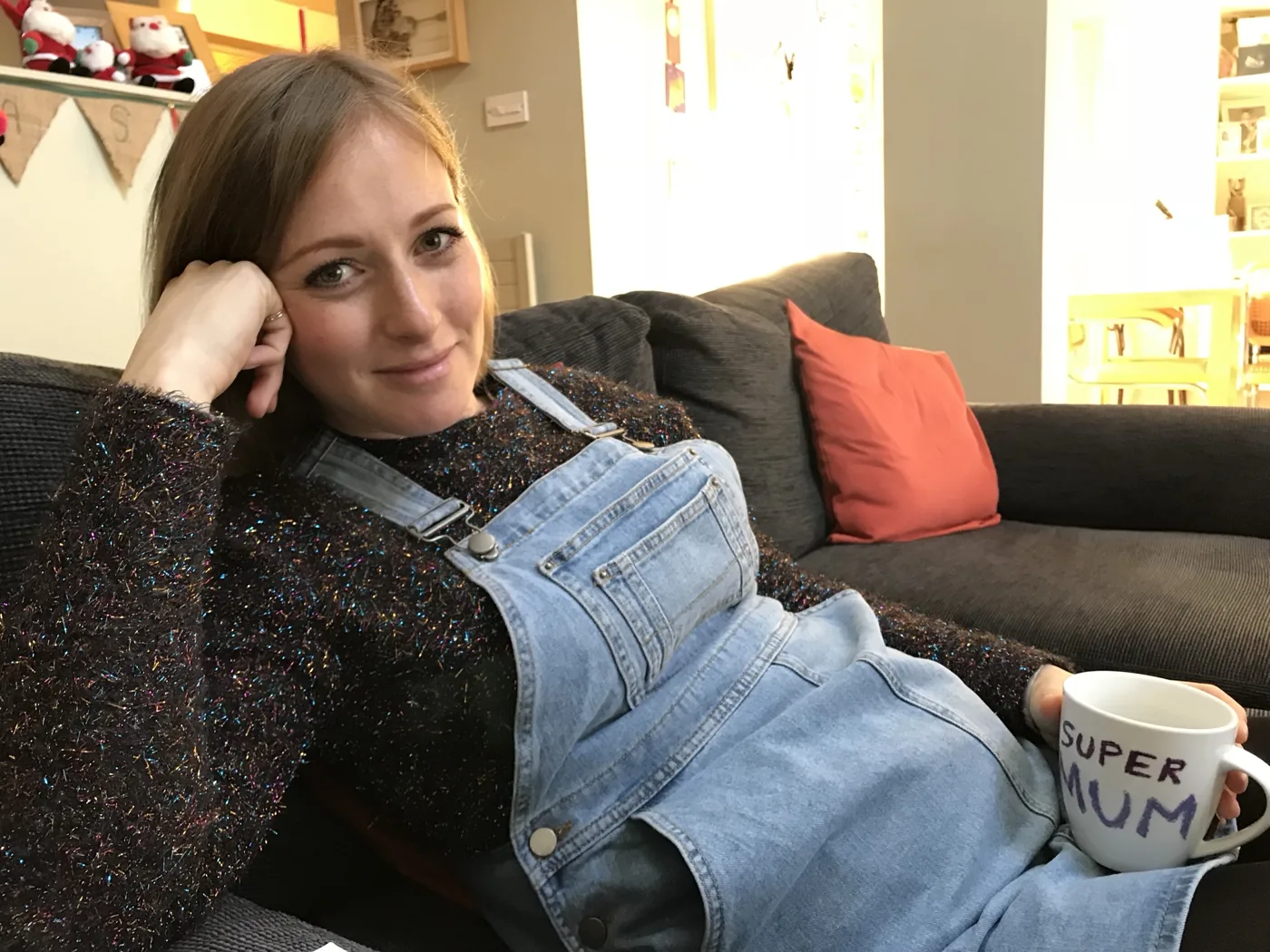 Rhian Penford relaxing on the sofa with a Super Mum mug